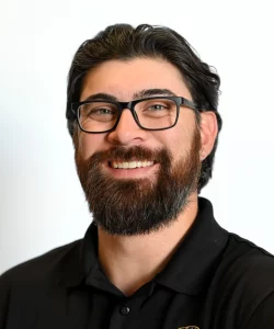 Man with dark hair, beard and glasses